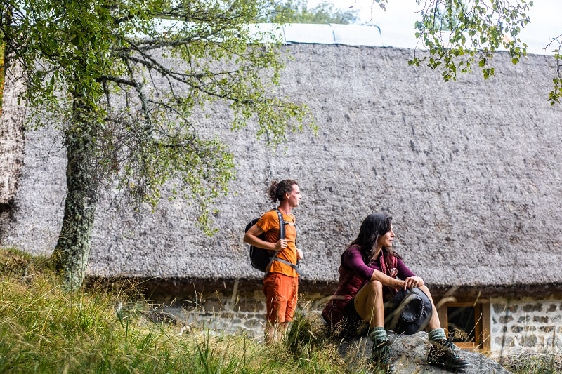 Deux randonneurs prennent une pause devant une jasserie typique du Livradois-Forez